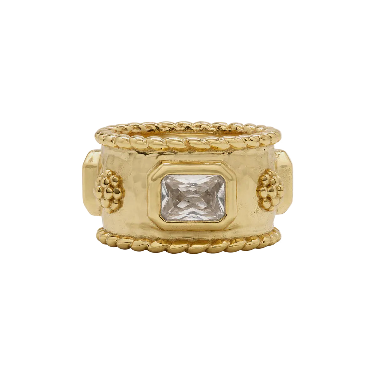 A wide yellow gold ring with a textured central panel, a rectangular clear gemstone, and decorative grape motifs on the sides, set against a light gray background.