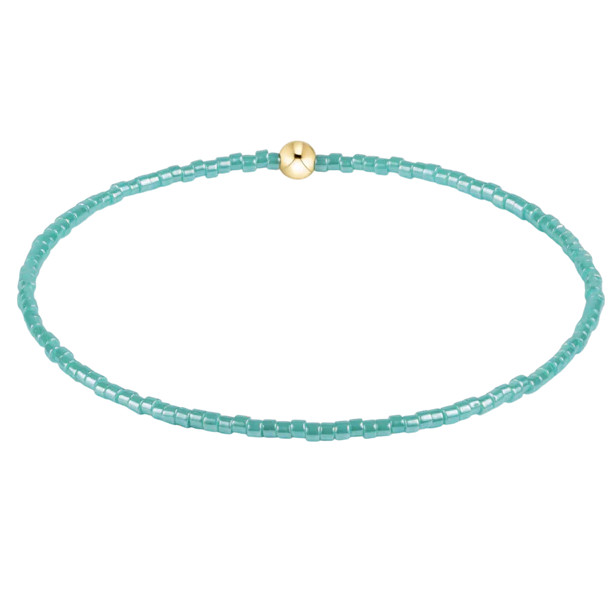 Turquoise beaded bracelet with a gold clasp on a white background