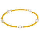 A yellow beaded bracelet with alternating white pearl-like beads and polished gold spacer beads, shown on a plain white background.