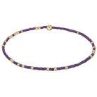 Purple beaded necklace with gold beads on a light gray background