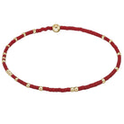 Red beaded necklace with gold beads on a light gray background