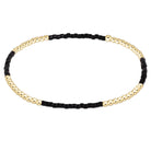 A beaded stretch bracelet featuring alternating sections of polished gold-tone round beads and matte black cylindrical beads, displayed on a clean white background.