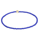 A beaded bracelet made of small, vibrant royal blue beads arranged in an oval shape, featuring a single polished gold-toned round bead at the top center, set against a plain white background.