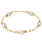 A gold beaded bracelet featuring five large white pearls spaced evenly along the band, set against a clean white background.